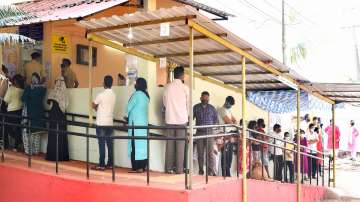 People stand in a queue to cast their votes, during the first phase of Goa Assembly polls, at a polling station, in Panaji.
