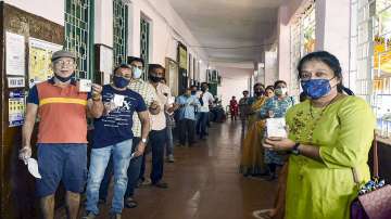 People holding their identification cards, stand in a queue to cast their votes during Goa assembly election 2022.