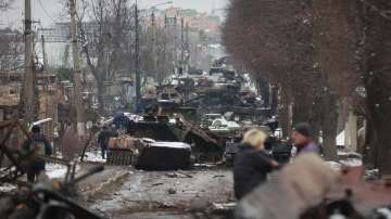 People look at the gutted remains of Russian military vehicles on a road in the town of Bucha, close to the capital Kyiv, Ukraine, Tuesday, March 1, 2022. 