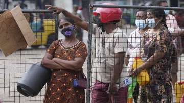 Sri Lankans wait in a queue to buy kerosene oil in Colombo