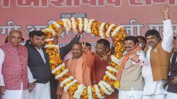UP Chief Minister Yogi Adityanath flashes the victory sign while being garlanded during a public meeting, for the ongoing UP Assembly elections at Sidharth Nagar, in Gorakhpur