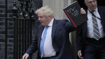 Britain's Prime Minister Boris Johnson waves to the media as he leaves 10 Downing Street for the House of Commons to make a statement about Downing Street parties.