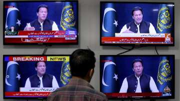 A man watches news channels broadcast a live address to the nation by Pakistan's Prime Minister Imran Khan, in Islamabad, Pakistan, Thursday, March 31, 2022.