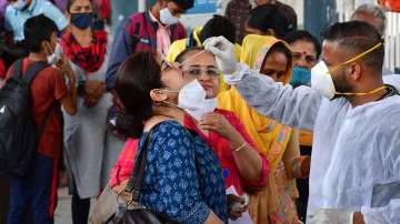 A healthcare worker collects swab sample of a passenger for Covid-19 test, at Dadar railway station, in Mumbai.