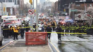 Law enforcement gather near the entrance to a subway stop in the Brooklyn borough of New York, Tuesday, April 12, 2022. Multiple people were shot and injured Tuesday at a subway station in New York City during a morning rush hour attack that left wounded commuters bleeding on a train platform.
