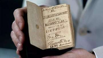 The book has tiny handwriting, intended to look like the font of a printing press