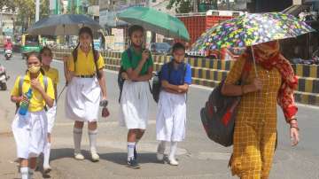 School students use umbrellas to shield themselves from the scorching sun on a hot summer day