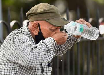 A pedestrian quenches his thirst on a hot summer day at Cannaught Place in New Delhi on Sunday.