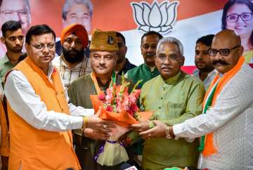 Uttarakhand Chief Minister Pushkar Singh Dhami and State BJP President Madan Kaushik present a bouquet to former AAP leader Colonel Ajay Kothiyal (retd) after he joined BJP, in Dehradun, Tuesday.