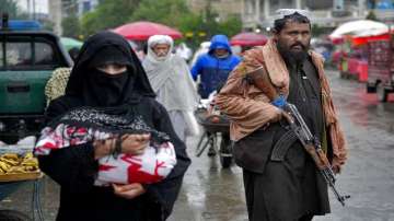 A Taliban fighter stands guard as people walk through the old market, in the city of Kabul, Afghanistan