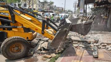 A bulldozer being used to demolish illegal structures during an anti-encroachment drive by the MCD, at Raghubir Nagar in New Delhi.