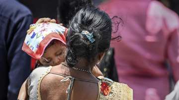 A woman covers the head of her child with a cloth to protect him from the scorching heat on a hot summer day in Mumbai