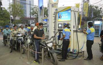 Petrol pump workers fill petrol in vehicles as fuel prices reduce.