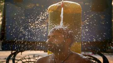 A man takes a bath under a public water tap on a hot summer day