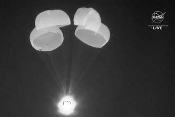 In this image made from video supplied by NASA, SpaceX Dragon capsule uses parachutes as it descends in the Gulf of Mexico. 