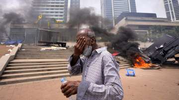 A Sri Lankan man reacts to tear gas as he walks past the vandalized site of anti-government protests outside President's office in Colombo, Sri Lanka, Monday, May 9, 2022. 