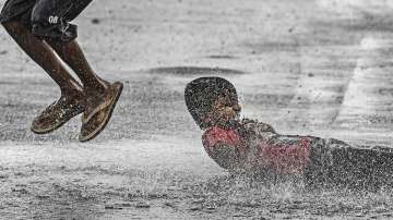 New Delhi: Boys play on a waterlogged road amid monsoon rains