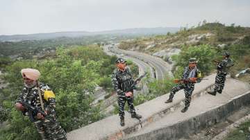 CRPF personnel stand guard at the Jammu–Srinagar National Highway as security convoy leaves for Kashmir in preparation for the Amarnath Yatra in Jammu