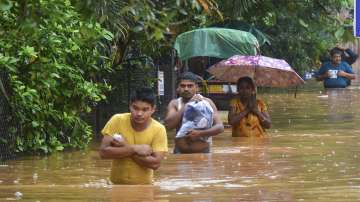 Commuters wade through a waterlogged area following heavy rain in Guwahati on Tuesday, June 14, 2022