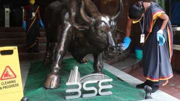 A woman cleans a bronze statue of a bull outside the BSE in Mumbai.