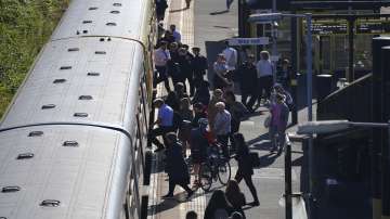 Passengers board a train at Hunts Cross Station, in Liverpool, England, Monday, June 20, 2022. Unions and train companies in Britain are set to hold last-minute talks Monday amid fading hopes of averting the country’s biggest rail strikes for decades.