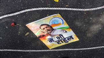 A poster lies on the road during a protest outside the AICC office against ED summons to party leader Rahul Gandhi in connection with the National Herald case