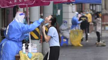 A worker takes a swab sample from a resident for a nucleic acid test in Huangpu District in Shanghai, China, on Tuesday, April 26, 2022.