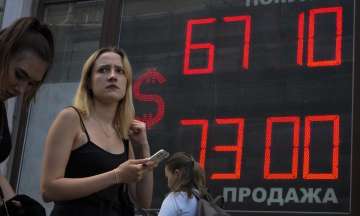 A woman walks past an exchange office screen showing the currency exchange rates of U.S. Dollar to Russian Rubles in St. Petersburg, Russia