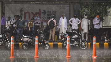 People take shelter under a bus stand amid monsoon rains, in New Delhi.