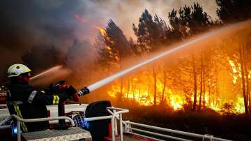 This photo provided Friday July 15, 2022 by the fire brigade of the Gironde region (SDIS 33) shows firefighters using hose to fight a wildfire near Landiras, southwestern France, Thursday, July 14, 2022.