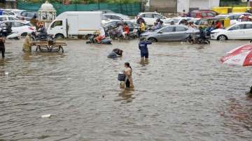 Commuters wade through a waterlogged area after heavy rainfall in Ahmedabad. 