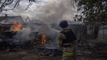 A firefighter hoses down a house on fire, after cluster rockets hit a residential area, in Konstantinovka, eastern Ukraine on Saturday, July 9, 2022.