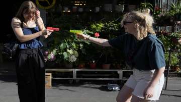 Tourists Jeanne, left, and Coraline, use water gun they just bought in a shop, to get fresh, as Europe is under an unusually extreme heat wave, in Paris, France. 