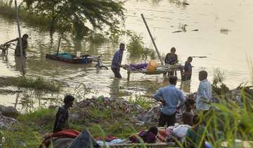 People living on the banks of Yamuna river shift their belongings after a rise in the water level of the river following monsoon rains, in New Delhi, Saturday, August 13, 2022.