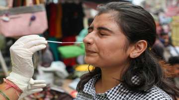 A healthcare worker collects a swab sample of a woman for Covid-19 test, in Jammu.