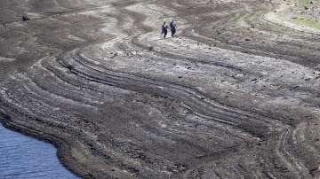 Members of the public walk in an area exposed by low water levels at Baitings Reservoir in Yorkshire as record high temperatures are seen in the UK, Ripponden, England, Friday, Aug. 12, 2022.