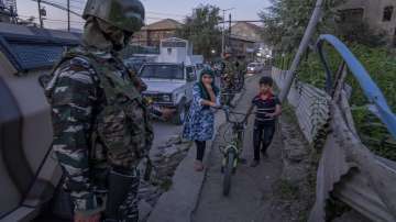 Kashmiri children walk past paramilitary soldiers near the site of a grenade explosion in Srinagar.
