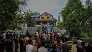 Kashmir villagers and police assemble outside the house of Sunil Kumar, a Kashmiri Pandit, who was shot dead by terrorists in the valley.