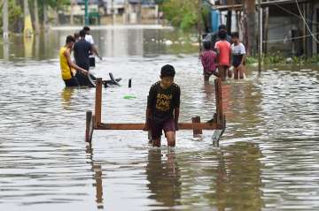 Migrants people carry their belongings through a waterlogged street in Bellandur, after heavy monsoon rains, in Bengaluru, Tuesday, Sep. 6, 2022.