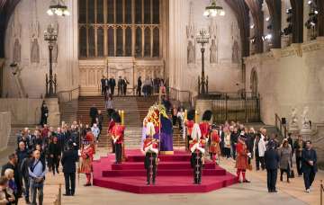 Members of the public file past the coffin of Queen Elizabeth II, draped in the Royal Standard with the Imperial State Crown and the Sovereign's orb and sceptre, lying in state on the catafalque in Westminster Hall
