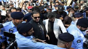 Former Pakistani Prime Minister Imran Khan, center, arrives to the Islamabad High Court surrounded by journalists and security in Islamabad, Pakistan.