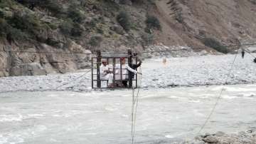 People cross a river on a suspended cradle, in Kalam Valley in northern Pakistan. 