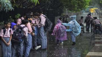 School students take shelter under trees during monsoon rain 