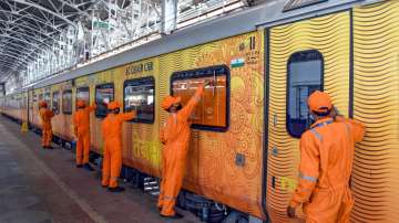 Workers clean a coach of Tejas Express train. 