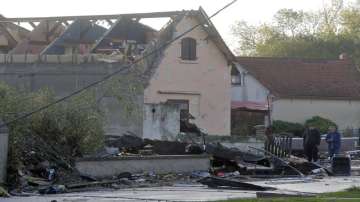 People stand next to a house whose roof was destroyed by a tornado, in Bihucourt, northern France. 