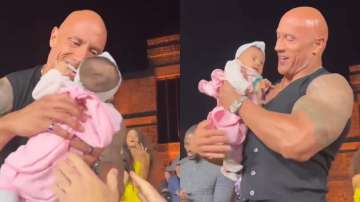Man handsover his baby to Dwayne Johnson at event