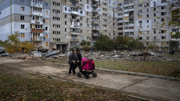 A couple pushing a baby stroller walks past a building damaged by a Russian missile in Mykolaiv, Sunday.