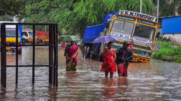 Commuters wade through a waterlogged road amid rainfall, in Chennai.