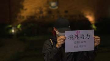 A protester holds up a paper which reads "Not foreign forces but internal forcers" and "Abuse of Government power plunge the people into misery and suffering" during a gathering at the University of Hong Kong in Hong Kong, Tuesday, Nov. 29, 2022.