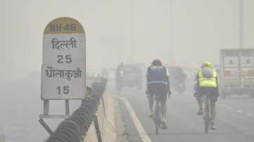 
People ride bicycles on Gurugram-Delhi Expressway amid low visibility due to smog in Gurugram on Thursday, November 3, 2022.